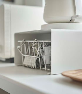 Close up of white Yamazaki Home Stackable Countertop Shelf with a basket of tea underneath and a kettle above view 8