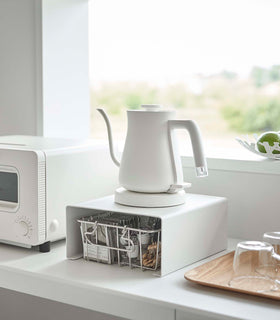 White Yamazaki Home Stackable Countertop Shelf with a kettle above and a basket underneath view 2