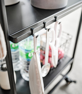 Close up of black Rolling Utility Cart hooks holding kitchen tools by Yamazaki Home. view 12