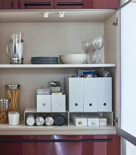 Front view of white Yamazaki Home Shelf Risers in a cabinet containing water bottles and wrap boxes view 3