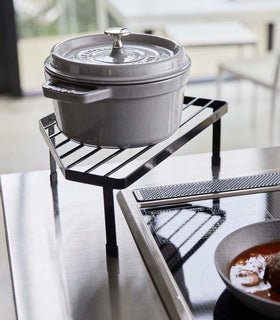 Black Corner Riser holding pot next to kitchen stovetop by Yamazaki Home. view 10