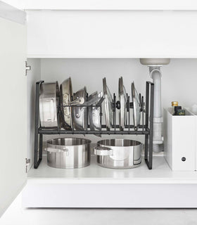 Front view of black Yamazaki Home Adjustable Pots and Pans Organizer underneath a sink storing pots and lids view 11