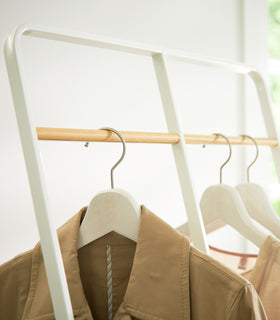 Close up top view of white 2-level Coat Rack displaying clothes by Yamazaki Home. view 6