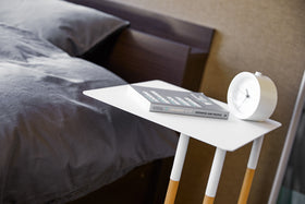 Close up view of white C Side Table displaying book and clock in bedroom by Yamazaki Home. view 5