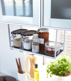 White Undershelf Organizer hanging from kitchen cabinet holding spices by Yamazaki Home. view 3