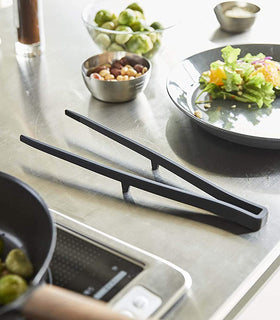 Black Floating Tweezer Tongs on kitchen countertop by Yamazaki Home. view 14