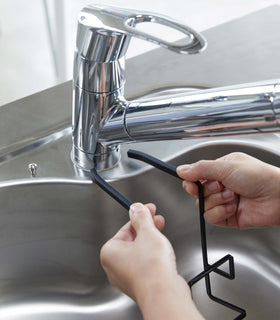 Black Faucet-Hanging Sponge Holder attatching to kitchen sink by Yamazaki Home. view 14