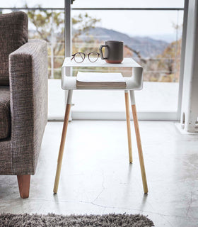 Front view of white Storage Table holding books, cup, and glasses in living room by Yamazaki Home. view 11