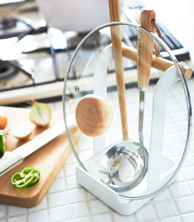 White Lid & Ladle Stand holding tongs, ladle, and pot cover on kitchen counter by Yamazaki Home. view 4