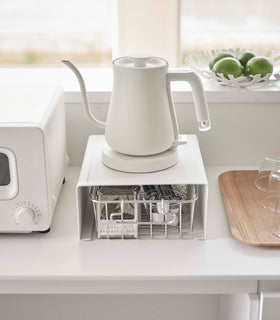 White Yamazaki Home Stackable Countertop Shelf with a basket of tea underneath and a kettle above view 7