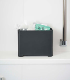 Frontal view of black Yamazaki Self-Draining Bathroom Organizer filled with bath supplies view 15