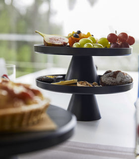 Front view of black Stackable Serving Stand stacked and displaying fruits and pastries on kitchen table by Yamazaki Home. view 9