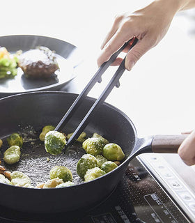 Black Floating Tweezer Tongs holding brussel sprout in kitchen by Yamazaki Home. view 17