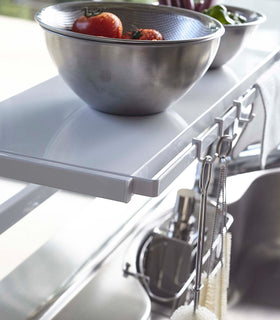 Close up of white Expandable Countertop Organizer displaying bowls and cleaning utensils by Yamazaki Home. view 7