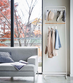 Hats and clothes hung on white Yamazaki Home Coat Rack with Hat Storage view 3