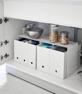 Yamazaki White Under-Cabinet Storage Shelves holding bowls and baskets on top and four storage boxes underneath. view 3