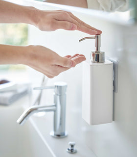 Dispensing soap from white Yamazaki Home square soap onto hands view 4