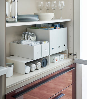 White Yamazaki Home Shelf Risers in a cabinet containing water bottles and wrap boxes view 2