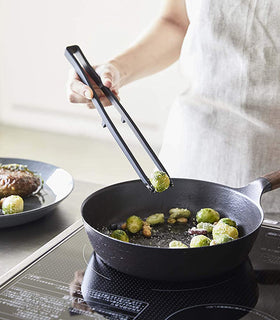 Black Floating Tweezer Tongs being used to cook in kitchen by Yamazaki Home. view 18