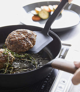 Close up view of black Floating Spatula picking up hamburger in kitchen by Yamazaki Home. view 11