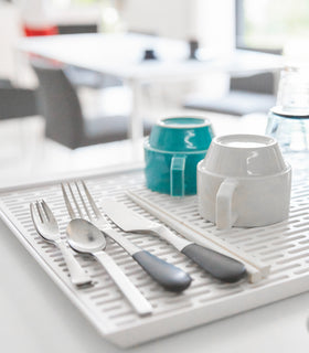 Closeup view of white Dish Drainer Tray holding silverware and glasses by Yamazaki Home. view 4