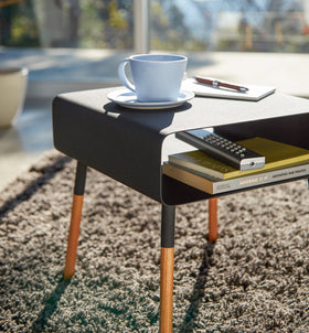 Close up view of black Storage Table containing books and displaying cup by Yamazaki Home. view 22