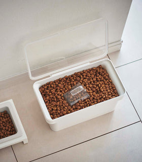 Aerial view of open white Airtight Food Storage Container holding pet food next to white Pet Food Bowl by Yamazaki Home. view 6