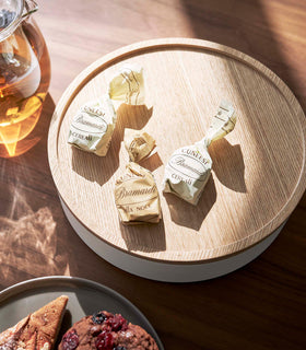 Close up of Yamazaki Home large, low white Storage Case closed with candy on top on a dining table beside pastries and tea view 4