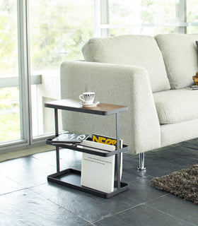 Black End Table holding coffee cup and books in living room by Yamazaki Home. view 4