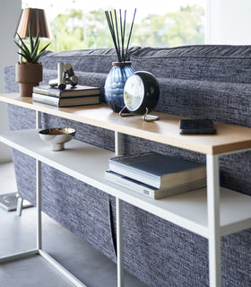 Close up of white Yamazaki Home Long Console Table - Shelf  with books and decorations on it view 21