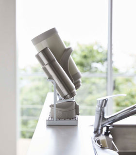 Side view of white Countertop Bottle Drying Rack holding water bottles in kitchen by Yamazaki Home. view 4