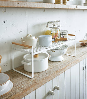 Front right diagonal view of white wired organizer rack holding cups, jars, and bowls. view 3