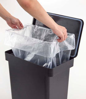 Person inserting bag into black Rolling Trash Can on white background by Yamazaki Home. view 14