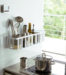 White Magnetic Storage Basket holding spices, oils, and utensils in kitchen by Yamazaki Home. view 2