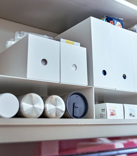 White Yamazaki Home Shelf Risers in a cabinet containing water bottles and food wrap boxes view 6