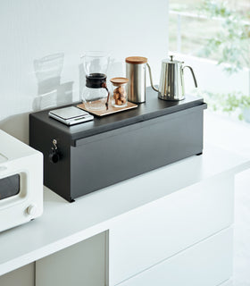 Side view of black Yamazaki Home Bread Box - Wide on a counter with bread and snacks inside view 10