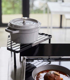 Black Corner Riser holding pot next to stovetop by Yamazaki Home. view 9