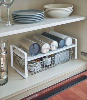 White Expandable Countertop Organizer expanded holding bottles in kitchen cabinet by Yamazaki Home. view 2