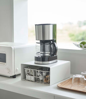 White Yamazaki Home Stackable Countertop Shelf with a coffee pot above and a basket underneath view 3