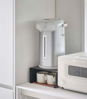 Black Yamazaki Home Stackable Countertop Shelf with a water dispenser above and cups underneath view 13