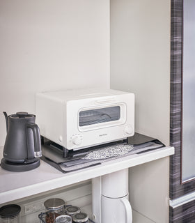 Black Magnetic Placemat Organizer holding mats under toaster oven by Yamazaki home. view 12