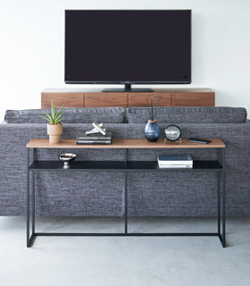 Frontal image of black Yamazaki Home Long Console Table - Shelf with books and decorations on it view 28