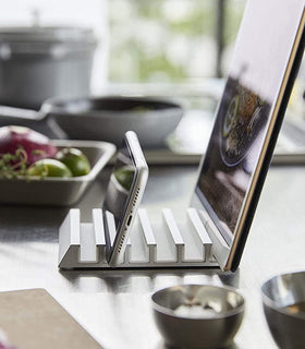 Side view of white Phone and Tablet Stand holding phone and tablet on kitchen counter by Yamazaki Home. view 6