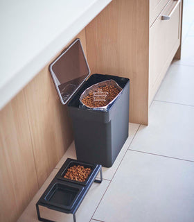 Open black Airtight Food Storage Container holding pet food next to black Pet Food Bowl by Yamazaki Home. view 37