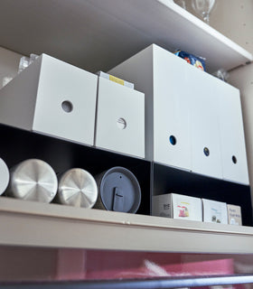 Close up of black Yamazaki Home Shelf Risers in a cabinet storing water bottles and wrap boxes view 12