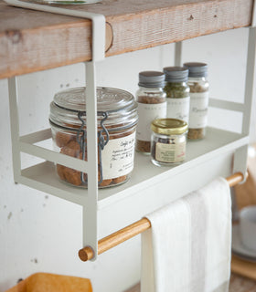 Side view of white Undershelf Organizer in kitchen holding ingredients and towel by Yamazaki Home. view 5