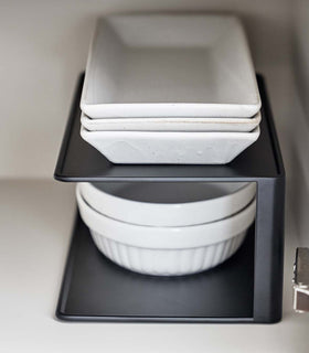 Close up of black Yamazaki Two-Tier Cabinet Organizer with plates and bowls on a shelf view 10