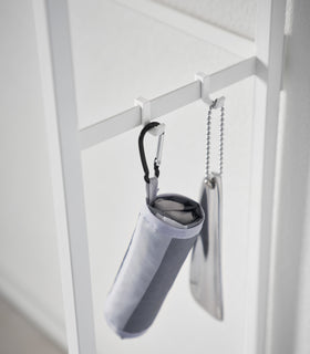 A folding umbrella and shoe horn hanging form the side hooks on the Long Console Table by Yamazaki Home in white. view 7