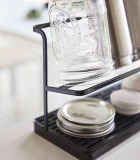 Close up end view of black Countertop Bottle Drying Rack holding mason jar and cover by Yamazaki Home. view 12