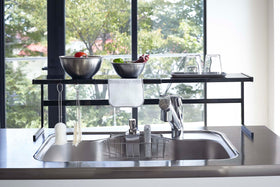 Front view of black Expandable Kitchen Support Rack displaying kitchen items over stovetop by Yamazaki Home. view 14